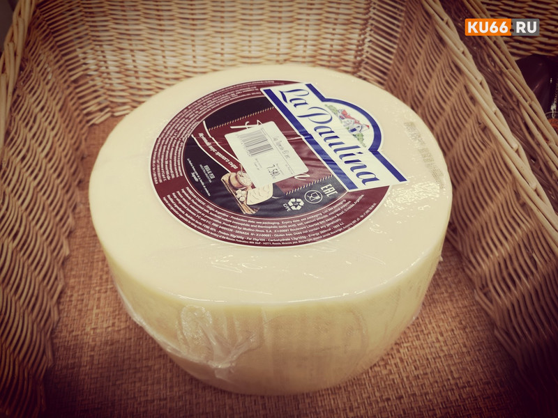 Женщина в белой куртке до колен с темным капюшоном вынесла из магазина "Магнит" в Каменске-Уральском 20 кусков сыра